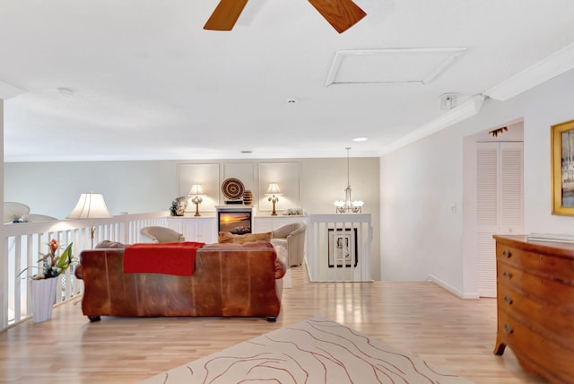 living room with light wood-style floors, attic access, ornamental molding, and a chandelier