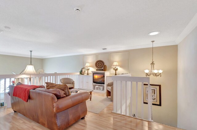 living area featuring a chandelier, crown molding, and light wood-style flooring