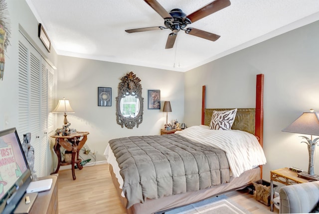 bedroom featuring light wood-style floors, a closet, a ceiling fan, and crown molding