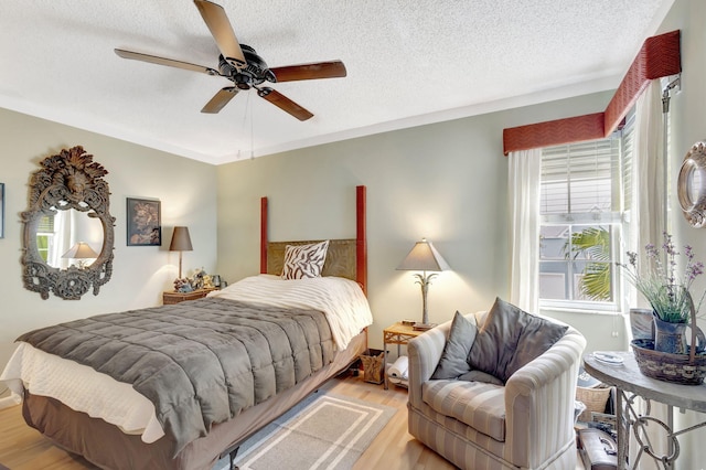 bedroom with light wood-style floors, ceiling fan, a textured ceiling, and ornamental molding