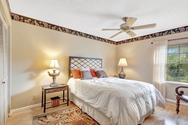 bedroom featuring light wood-type flooring, ceiling fan, a textured ceiling, and baseboards