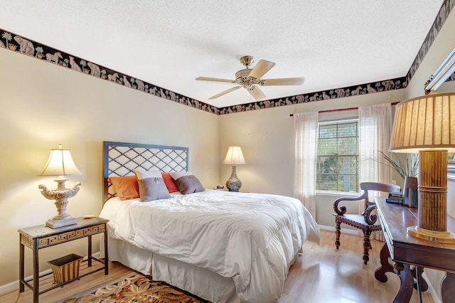 bedroom with a ceiling fan, a textured ceiling, baseboards, and wood finished floors