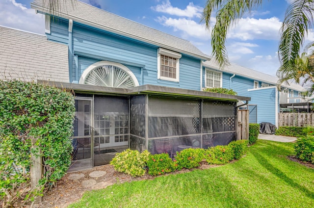 back of property with a sunroom, fence, and a yard