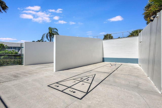 view of community with fence and shuffleboard