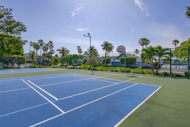 view of tennis court featuring community basketball court and fence