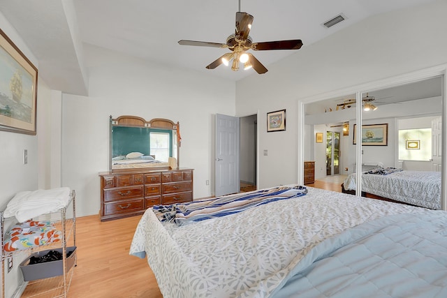 bedroom featuring a ceiling fan, visible vents, vaulted ceiling, and light wood-style flooring