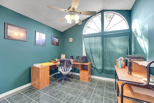 office area featuring a textured ceiling, dark tile patterned flooring, a ceiling fan, baseboards, and vaulted ceiling