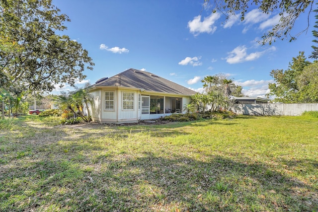 back of property featuring a lawn and fence