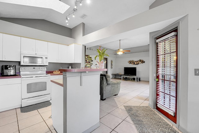 kitchen featuring vaulted ceiling with skylight, white appliances, open floor plan, and light tile patterned floors