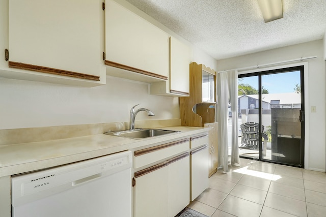 kitchen with light tile patterned floors, light countertops, white cabinetry, a sink, and dishwasher