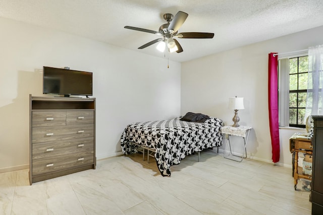 bedroom featuring ceiling fan, a textured ceiling, and baseboards