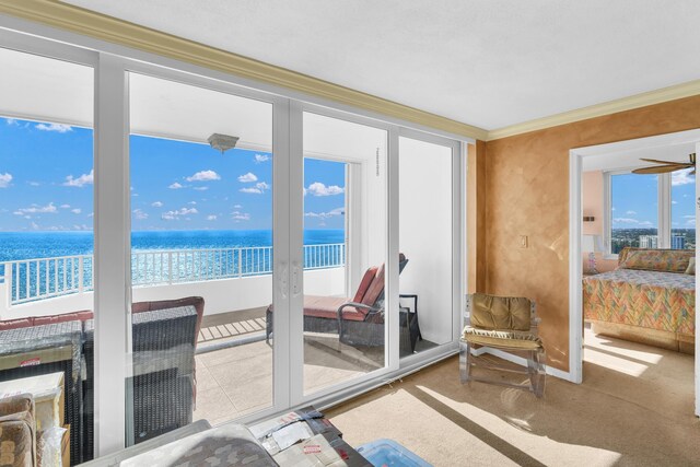 interior space with ornamental molding, a water view, and a beach view