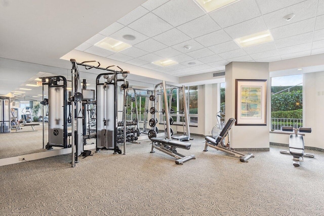 gym with a paneled ceiling, visible vents, and baseboards