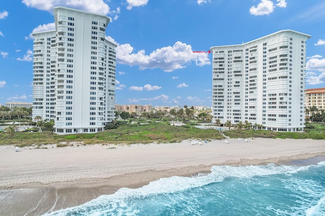 view of building exterior featuring a view of city, a water view, and a view of the beach