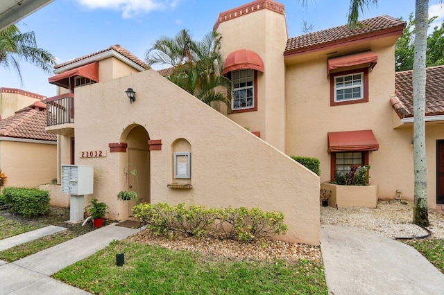 mediterranean / spanish-style home featuring a balcony, a tile roof, and stucco siding