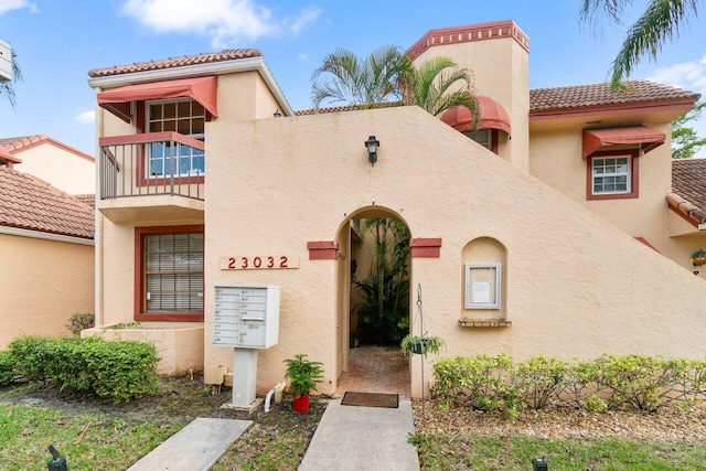 mediterranean / spanish-style house featuring a balcony, a tile roof, and stucco siding