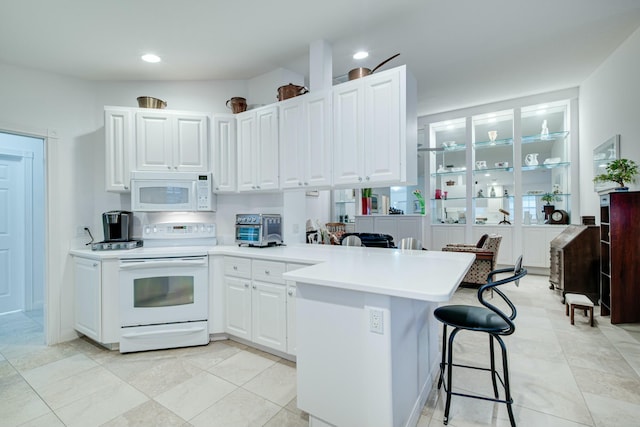 kitchen with white appliances, light countertops, a peninsula, and white cabinetry