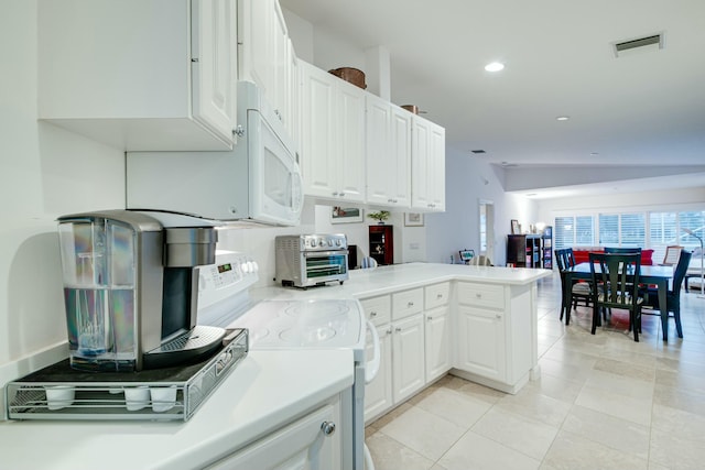 kitchen with a peninsula, white appliances, visible vents, white cabinets, and light countertops