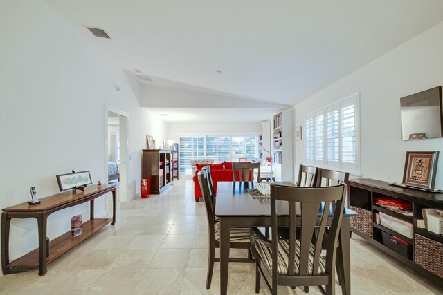 dining space featuring visible vents, vaulted ceiling, and light tile patterned flooring