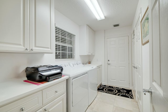 laundry area featuring light tile patterned floors, cabinet space, visible vents, washing machine and dryer, and a textured ceiling