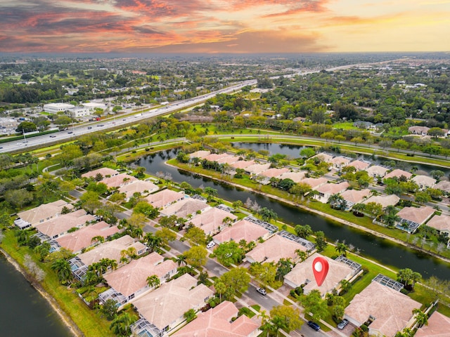 aerial view at dusk with a residential view and a water view