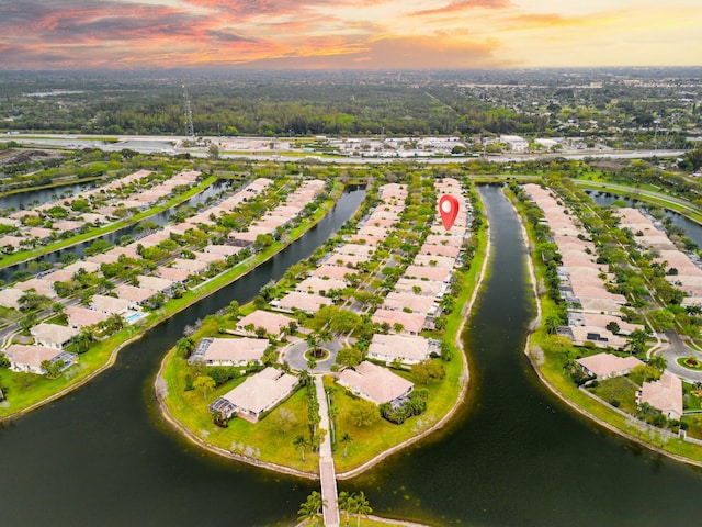 aerial view at dusk featuring a water view and a residential view