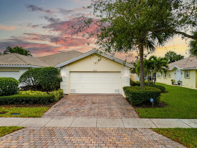 view of front of home featuring an attached garage, a yard, decorative driveway, and stucco siding