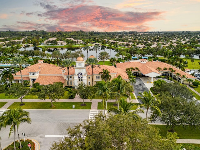 aerial view at dusk with a water view and a residential view