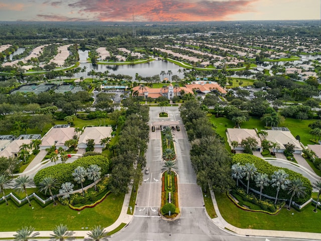 aerial view at dusk with a water view and a residential view