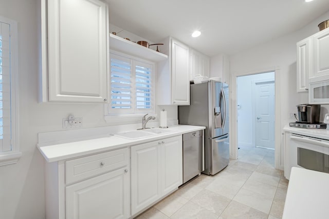 kitchen featuring white cabinets, stainless steel appliances, light countertops, a sink, and recessed lighting