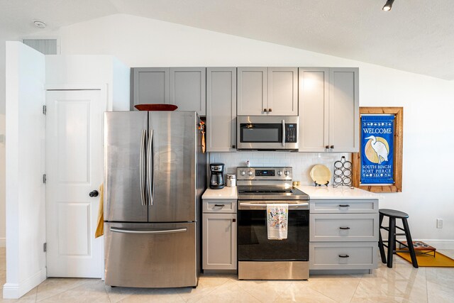 kitchen with lofted ceiling, visible vents, stainless steel appliances, and light countertops