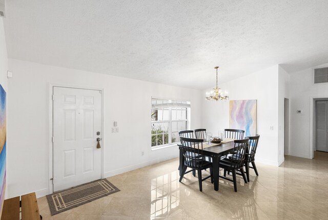 dining space with a notable chandelier, lofted ceiling, visible vents, a textured ceiling, and baseboards