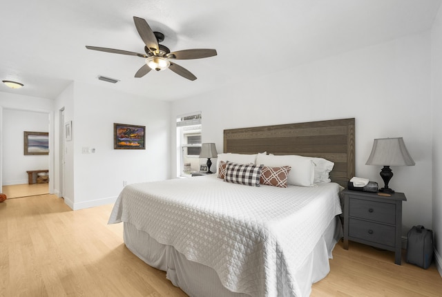 bedroom featuring light wood-style floors, baseboards, visible vents, and a ceiling fan