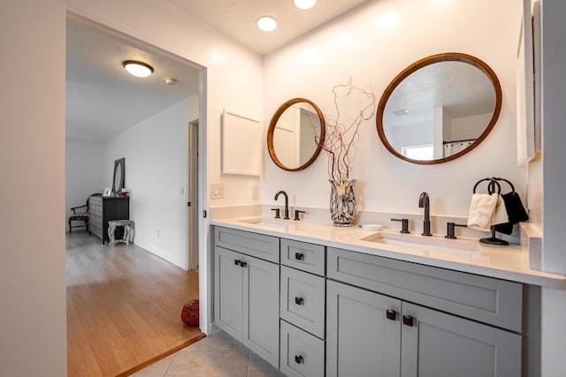 bathroom featuring a textured ceiling, double vanity, and a sink