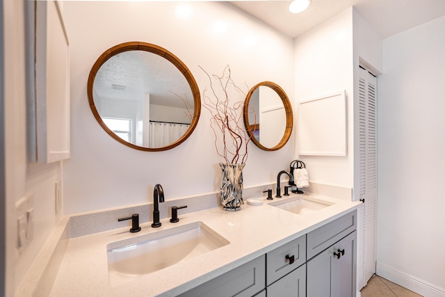 full bathroom featuring tile patterned flooring, a closet, a sink, and double vanity