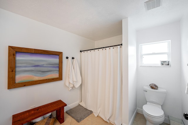 bathroom with visible vents, toilet, a textured ceiling, baseboards, and tile patterned floors