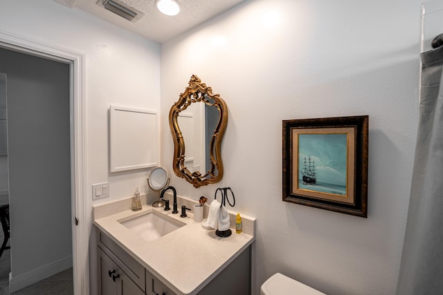 bathroom featuring visible vents, toilet, vanity, and a textured ceiling