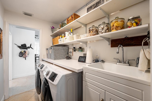 washroom with washing machine and dryer, visible vents, a sink, and light tile patterned flooring