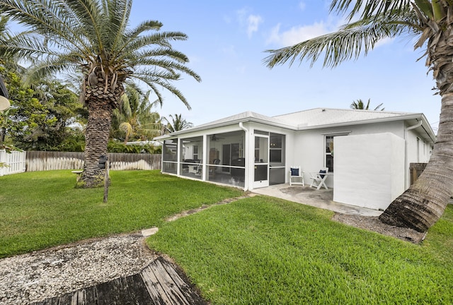 back of property with a patio, stucco siding, a lawn, a sunroom, and a fenced backyard