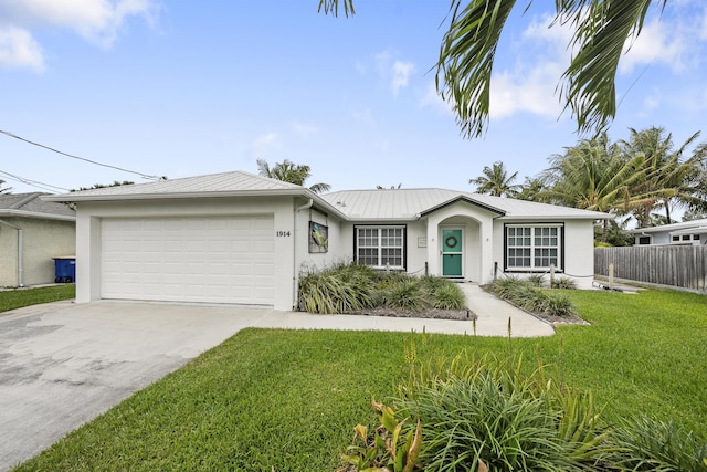 ranch-style house with driveway, metal roof, an attached garage, a front lawn, and stucco siding