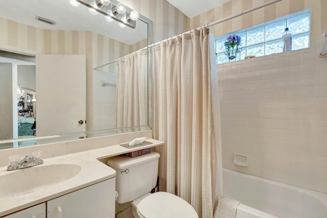 bathroom featuring visible vents, toilet, shower / bath combo with shower curtain, vanity, and wallpapered walls