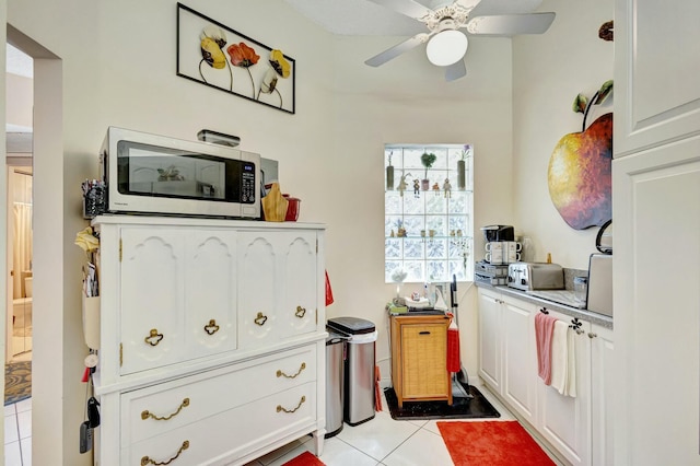 kitchen featuring ceiling fan, stainless steel microwave, white cabinets, and light tile patterned flooring