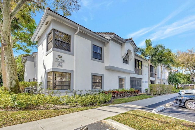 view of front of property with uncovered parking, a tiled roof, and stucco siding