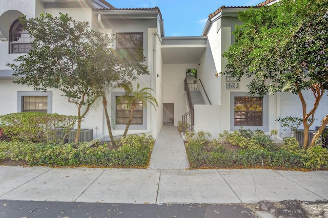 exterior space featuring a tiled roof, central AC, and stucco siding