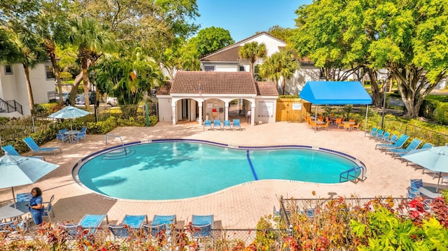 community pool with a patio area and fence