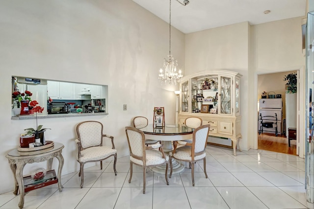 dining room featuring a chandelier, light tile patterned flooring, and a towering ceiling