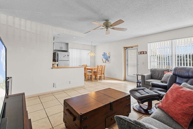 living room featuring light tile patterned floors, a textured ceiling, baseboards, and a ceiling fan