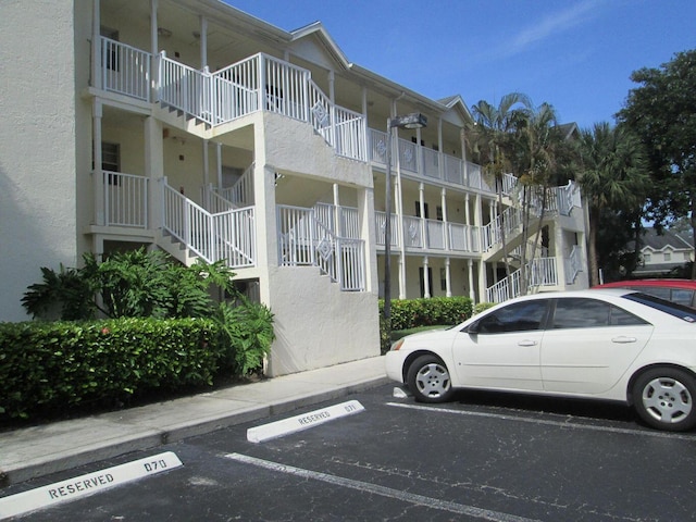 view of property featuring stairway and uncovered parking