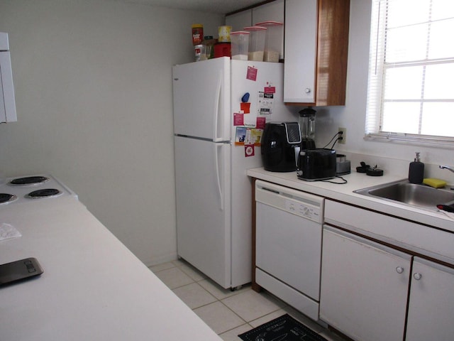 kitchen with light countertops, light tile patterned flooring, a sink, white cabinetry, and white appliances