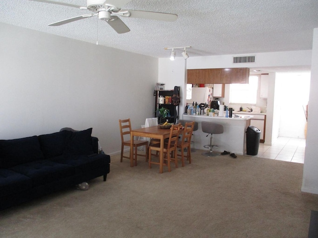 living room featuring track lighting, visible vents, light carpet, and a textured ceiling